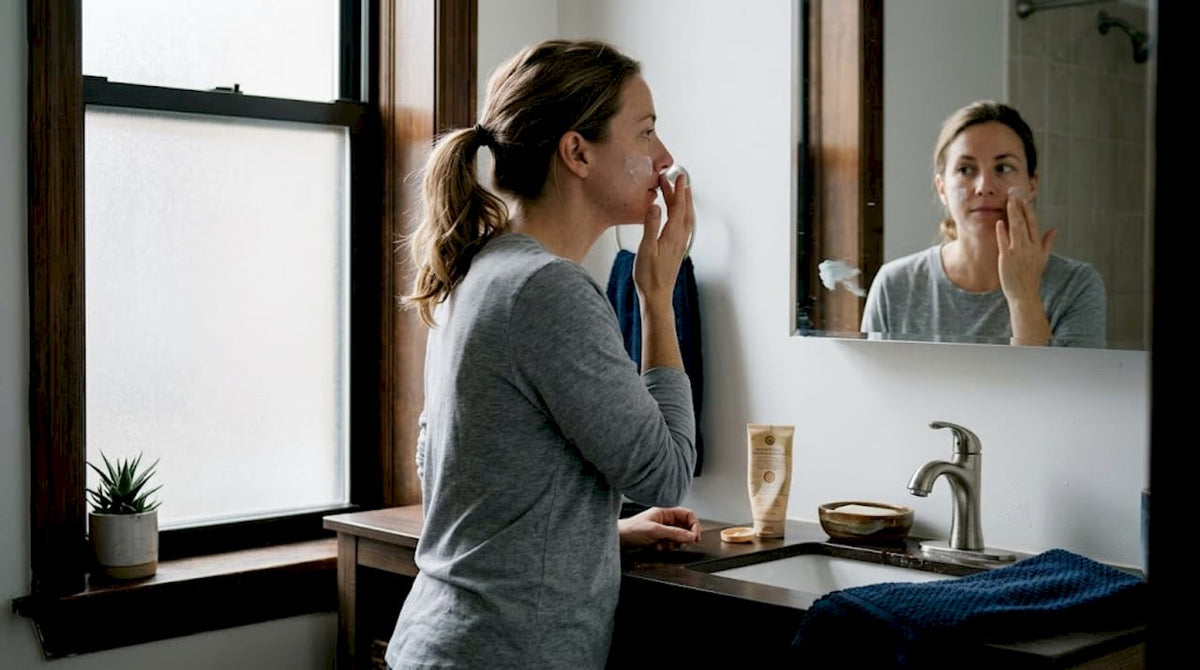 Woman applying morning skincare at bathroom sink
