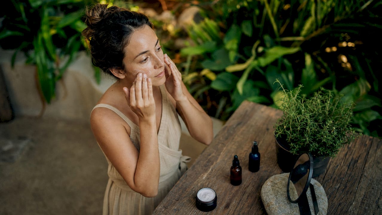 Woman applying moisturizer in bathroom