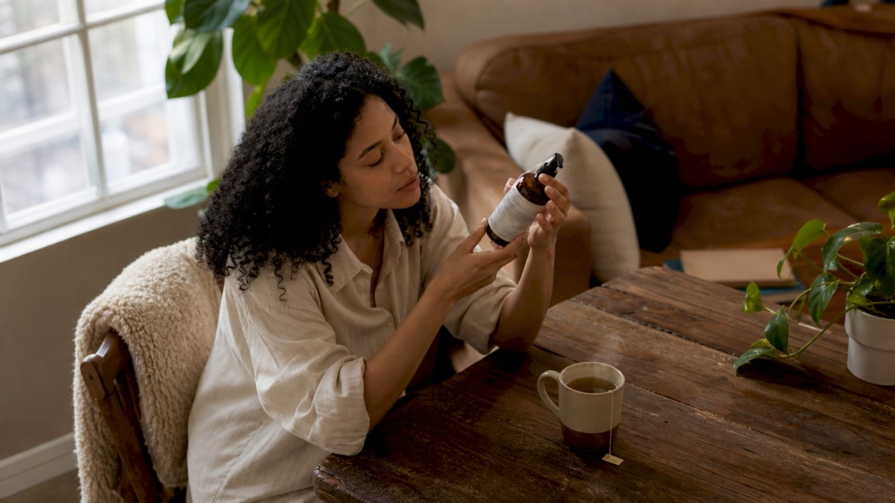 Woman closely reading skincare label at table