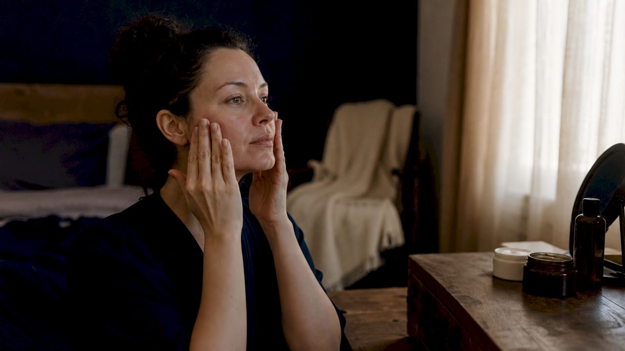 Woman applying moisturizer to irritated facial skin