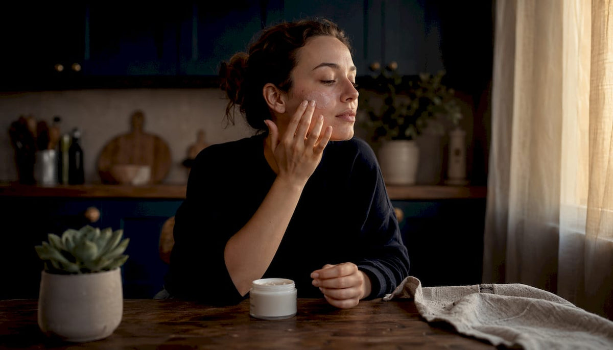 Woman applying cream on irritated facial skin