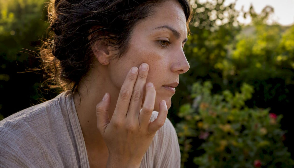 Woman inspecting facial hyperpigmentation on cheek