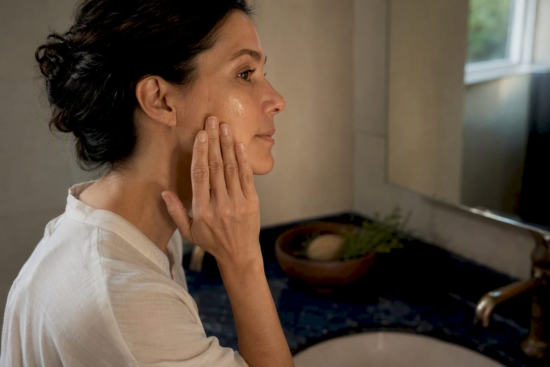 Hands applying firming serum on cheek