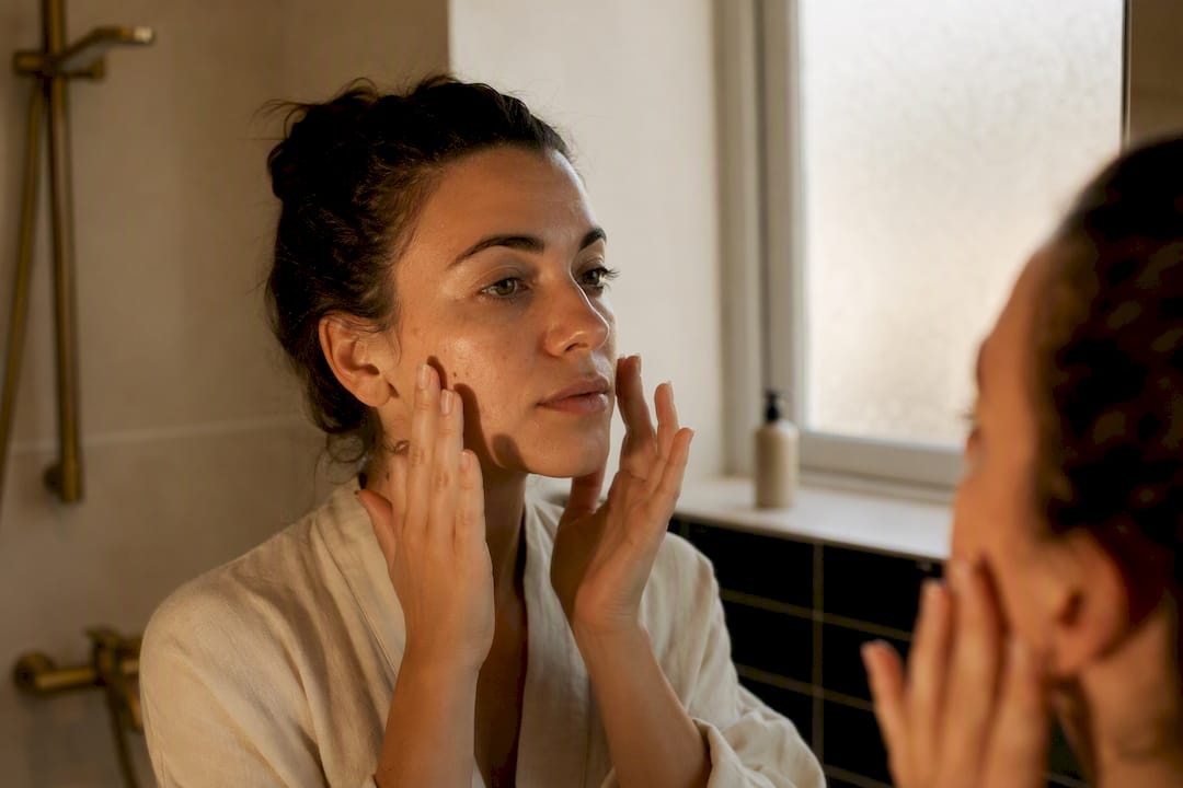 Hands applying serum to facial skin