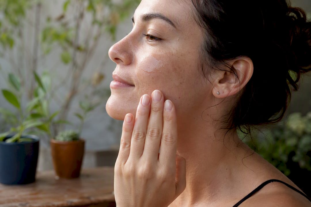Hands applying serum to face close-up