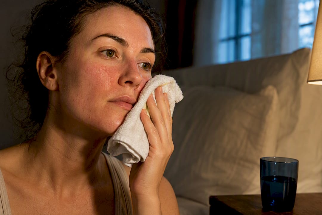 Adult using cool compress on flushed cheek