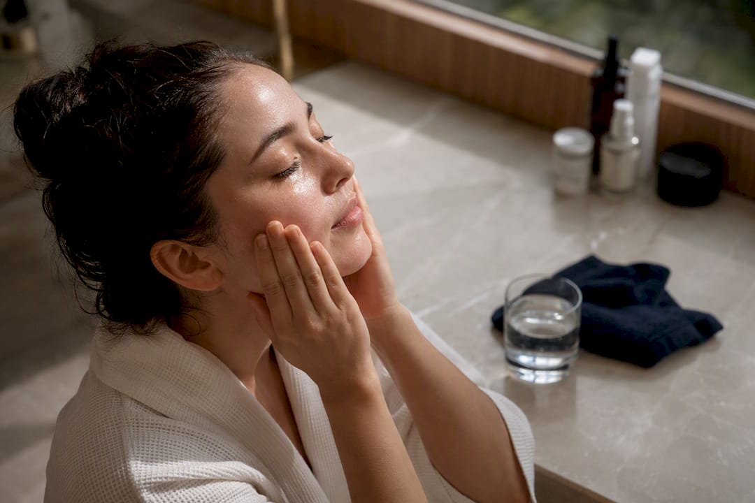 Hands pressing damp skin during skincare layering